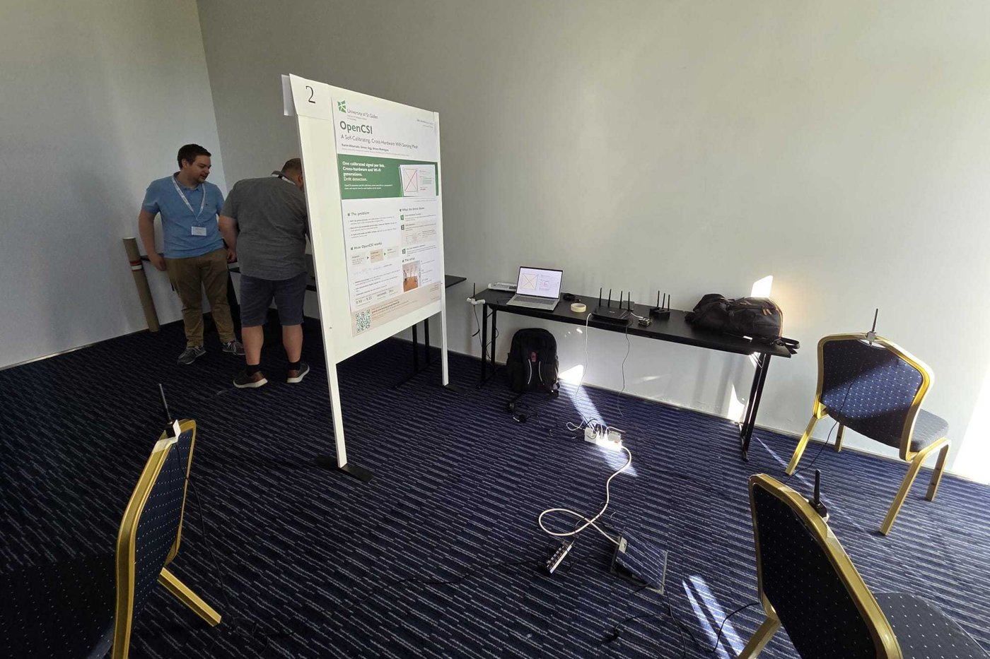 The OpenCSI demo booth with ESP32 nodes, the dashboard laptop, and the poster