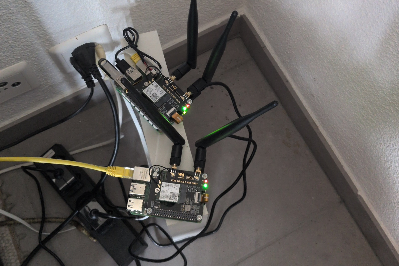 Two Raspberry Pi 5 boards with M.2 HATs carrying Intel AX210 cards and external antennas